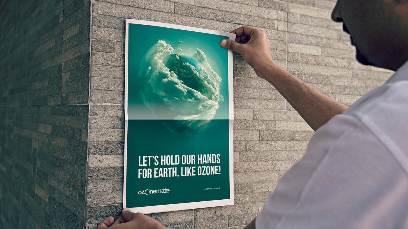 A man hangs a poster on a wall that says let 's hold our hands