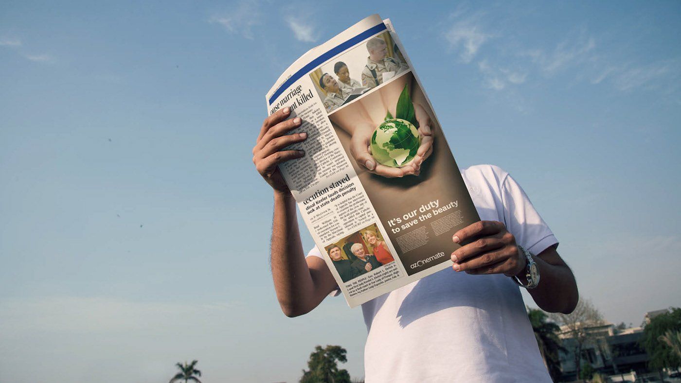 A man is holding a newspaper in front of his face