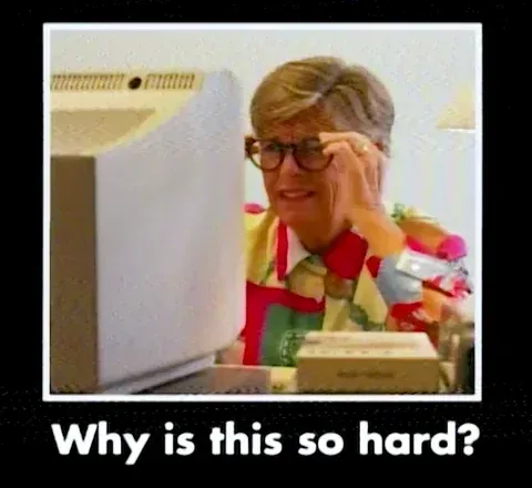 A woman wearing glasses is sitting in front of a computer confused