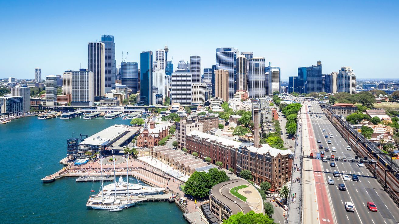 An aerial view of Sydney skyline with a harbor in the foreground.