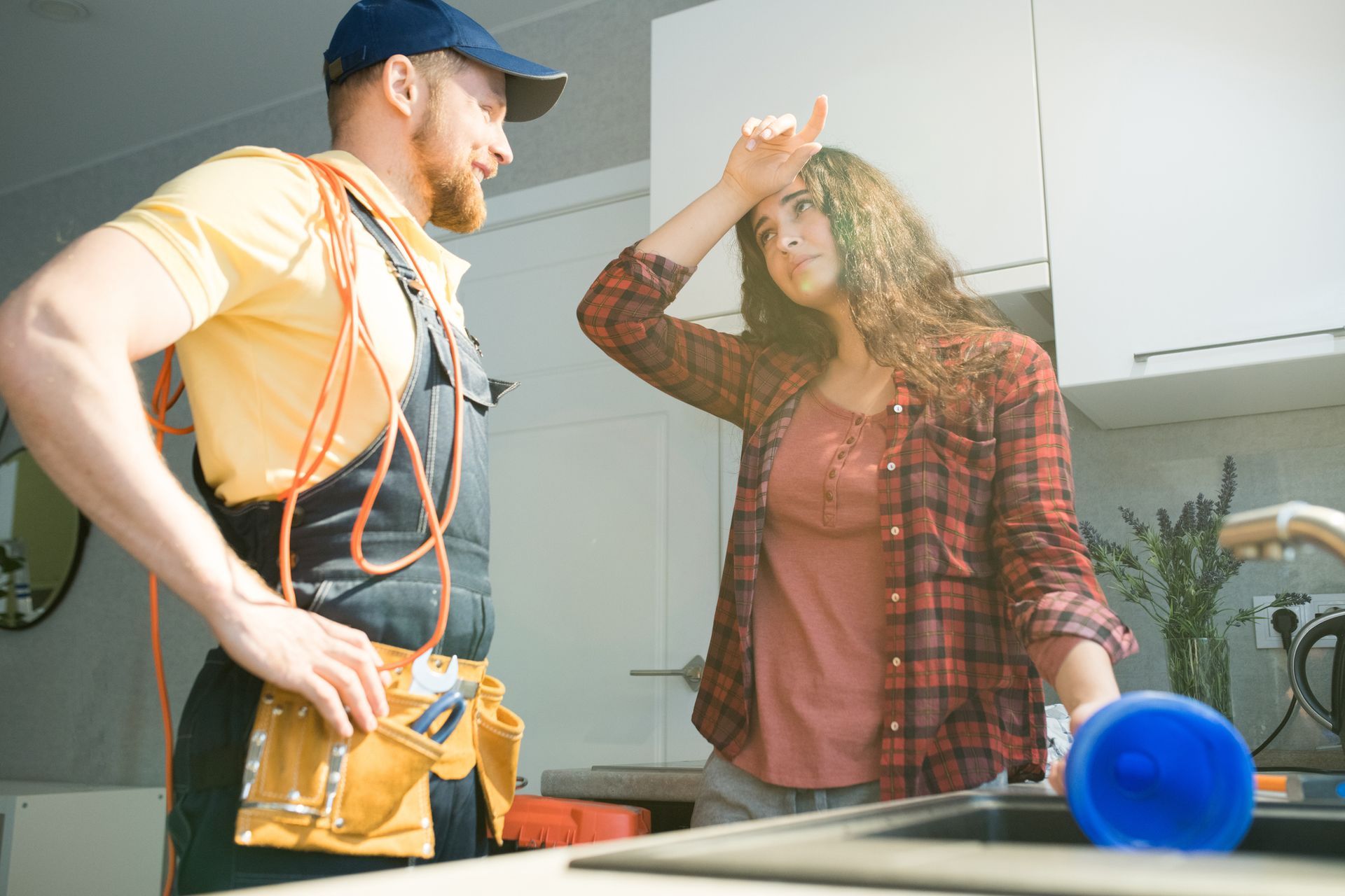 A woman dealing with clogged drains in the kitchen in Clayton, NC, from Rushin Plumbing