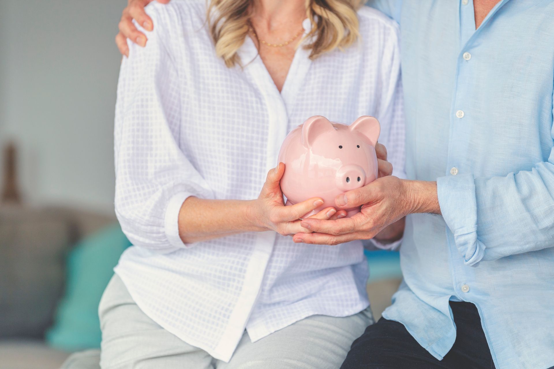 Mature couple holding a piggy bank in their new home, symbolising superannuation advice.