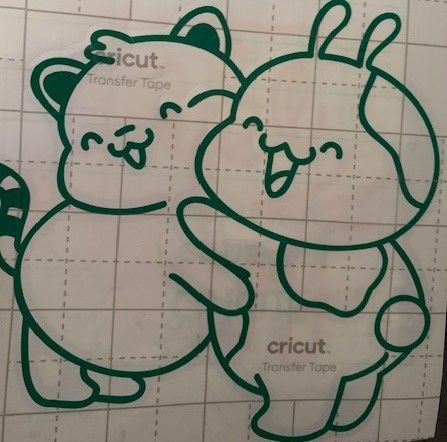 Green vinyl cutouts of two cartoon animals embracing; a raccoon and a dog.