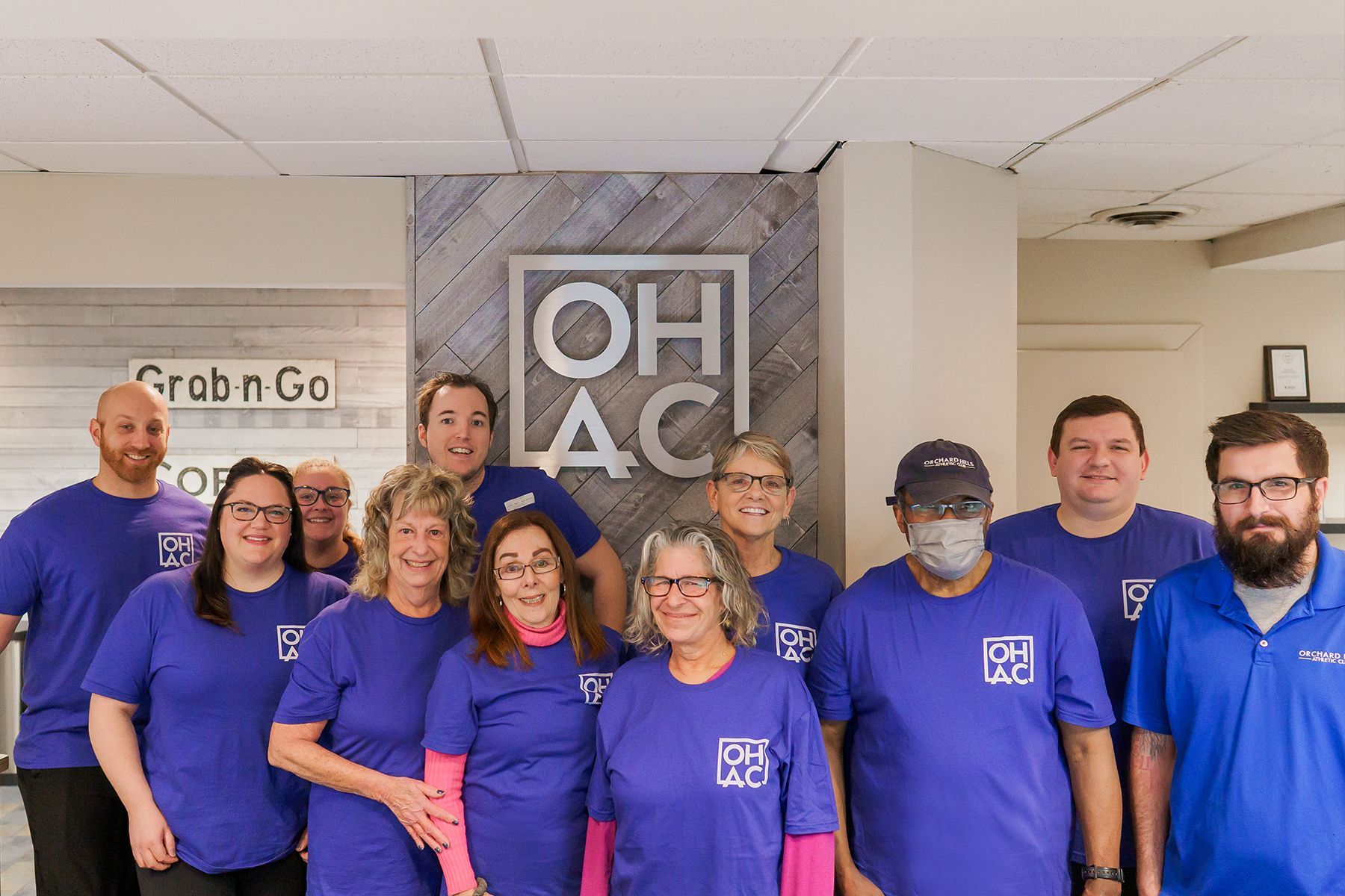 A group of people wearing purple shirts are posing for a picture.