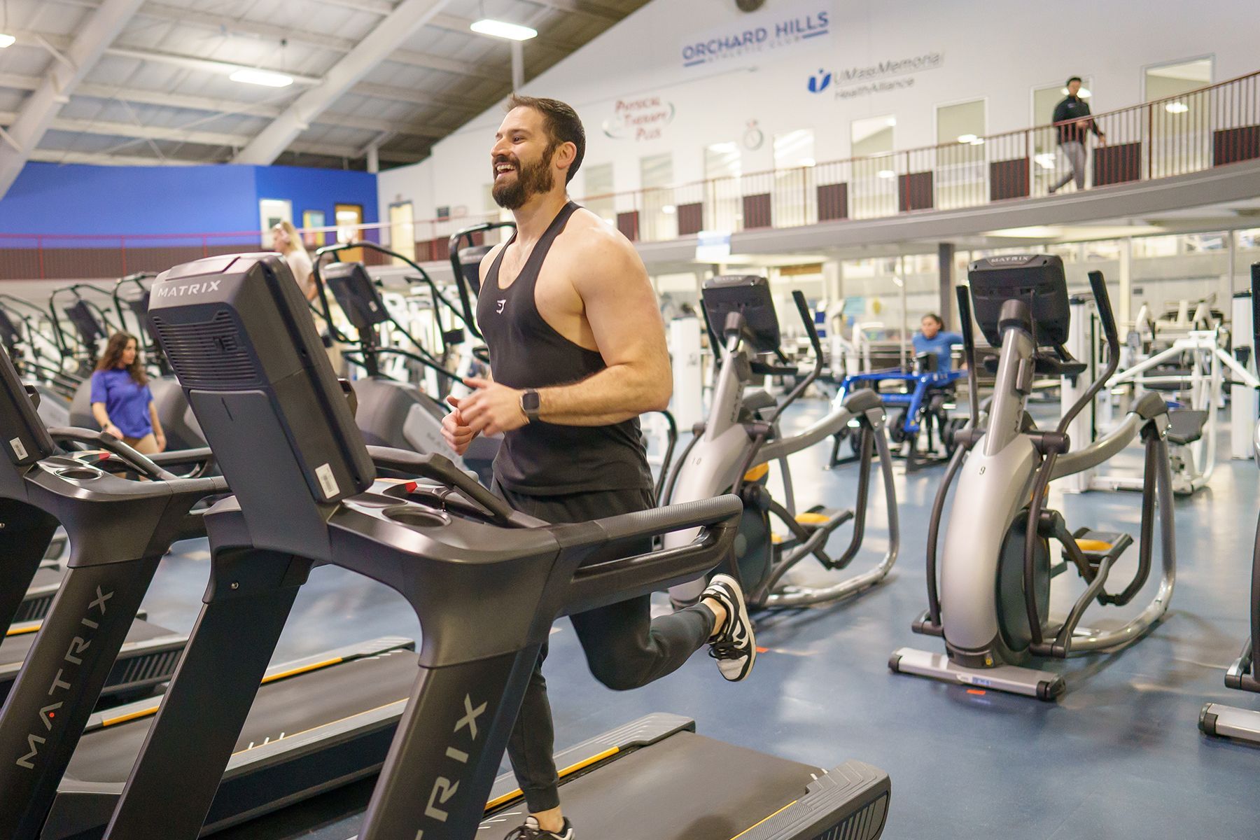A man is running on a treadmill in a gym.