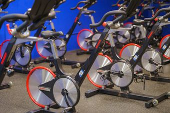 A bunch of exercise bikes are lined up in a gym.