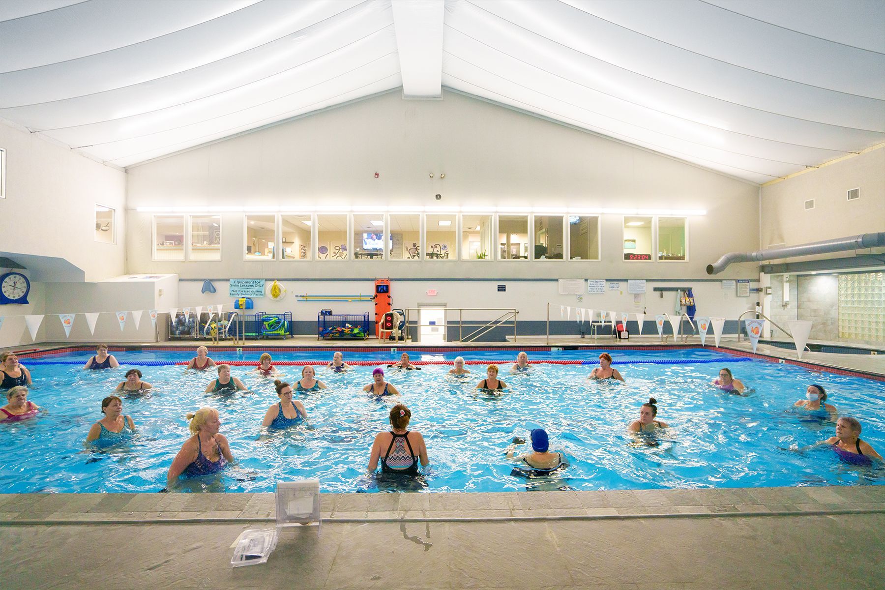 A group of people are swimming in a large indoor swimming pool.