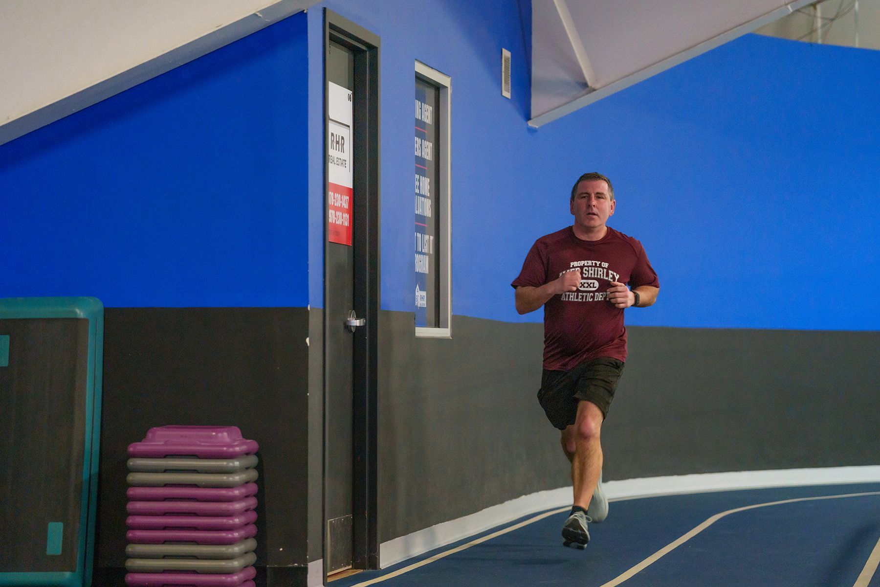 A man is running on a track in a gym.