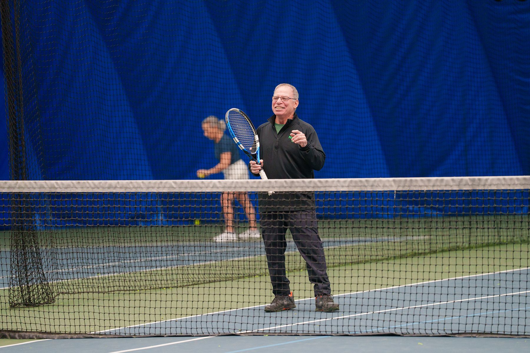 A man is standing on a tennis court holding a tennis racquet.