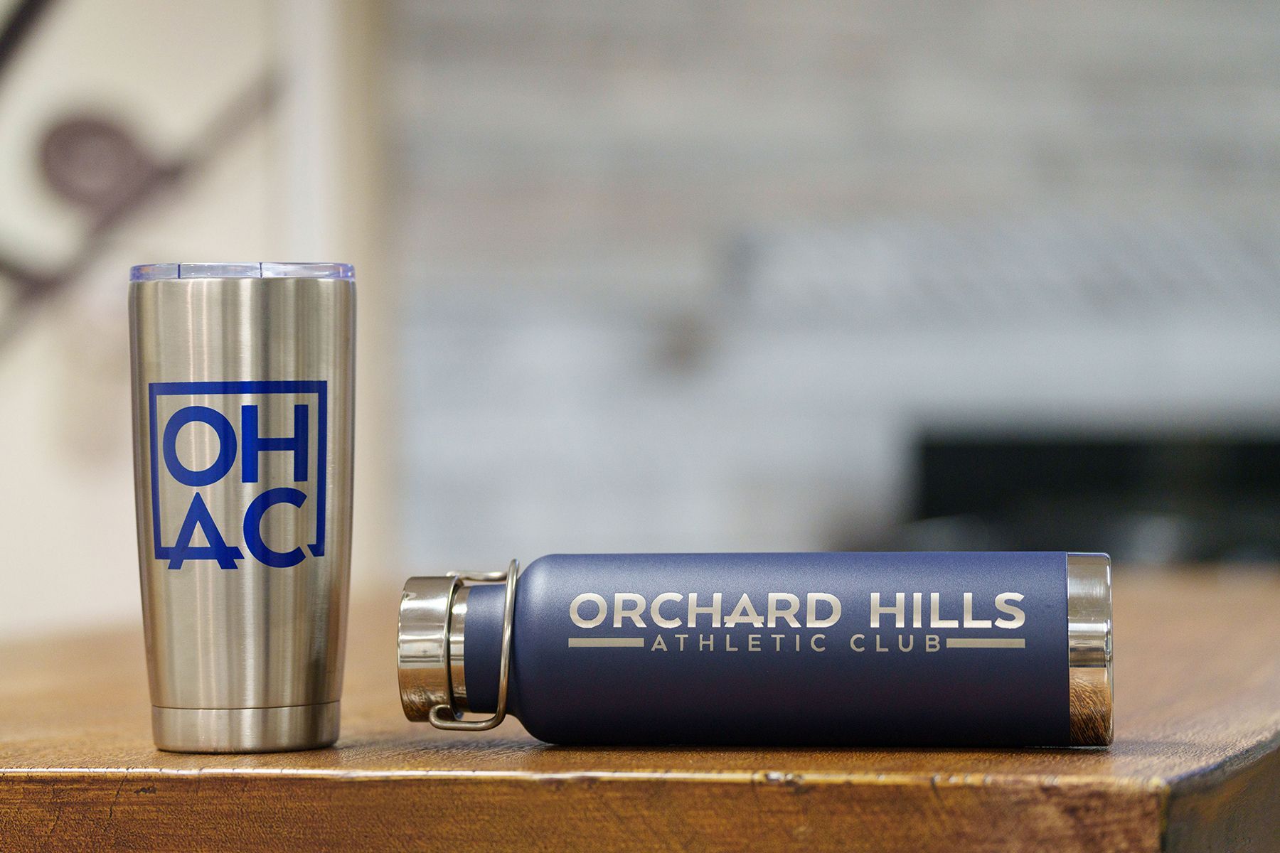 A stainless steel tumbler and a blue water bottle from the orchard hills athletic club