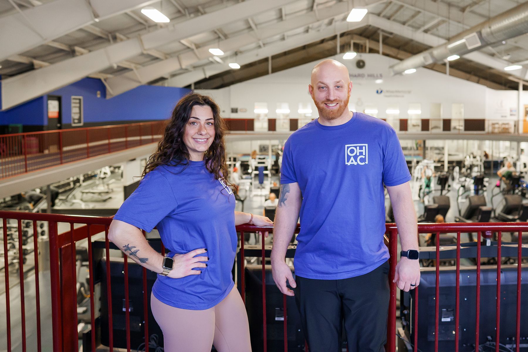 A man and a woman are standing next to each other in a gym.