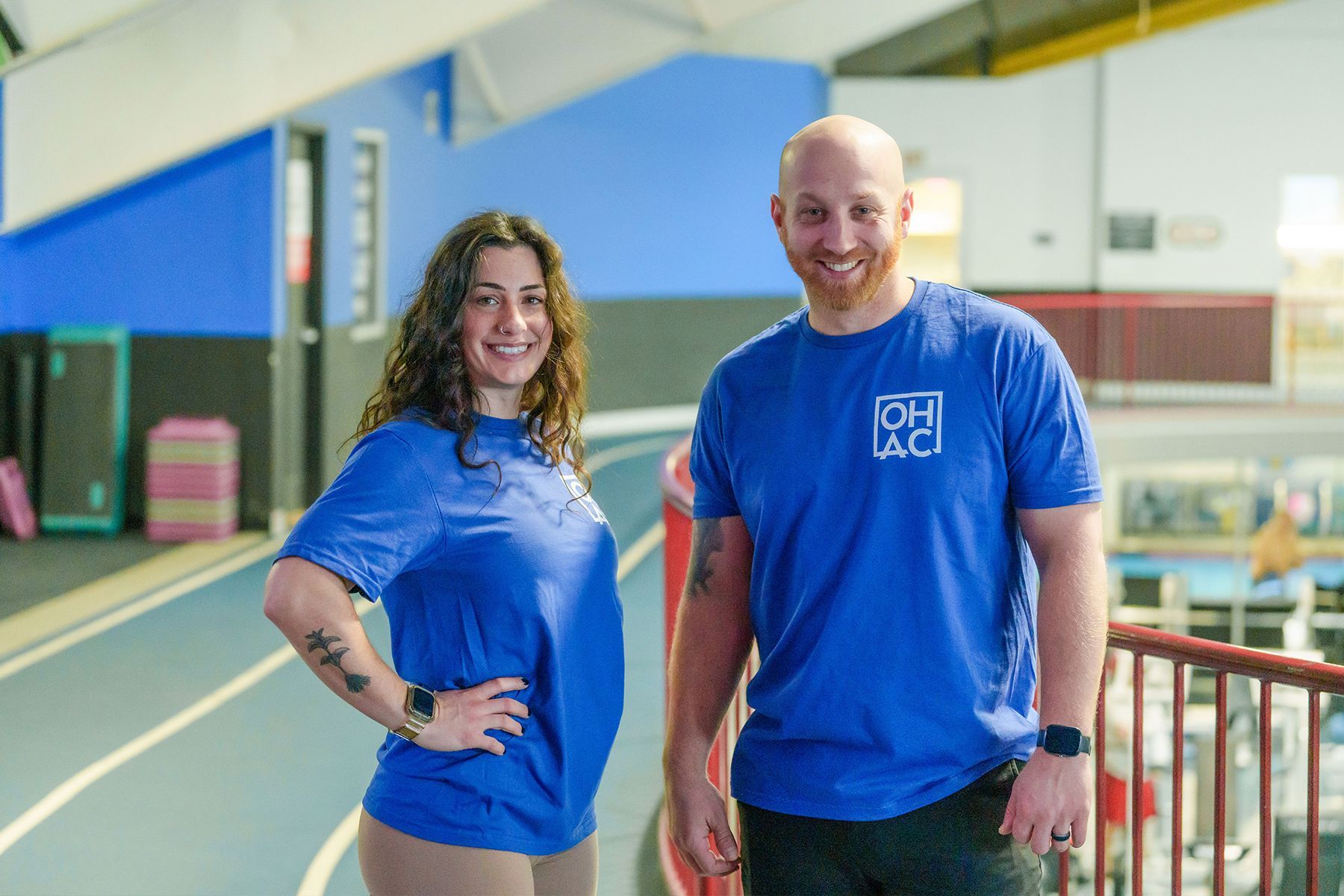 A man and a woman are standing next to each other in a gym.