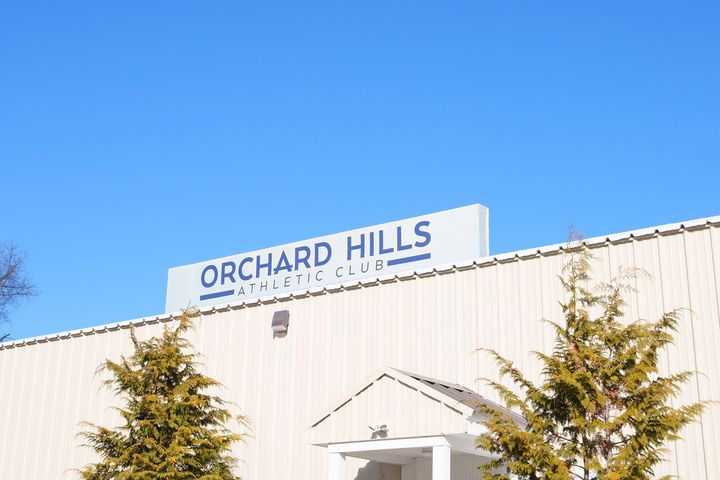 A white building with a blue sign that says orchard hills