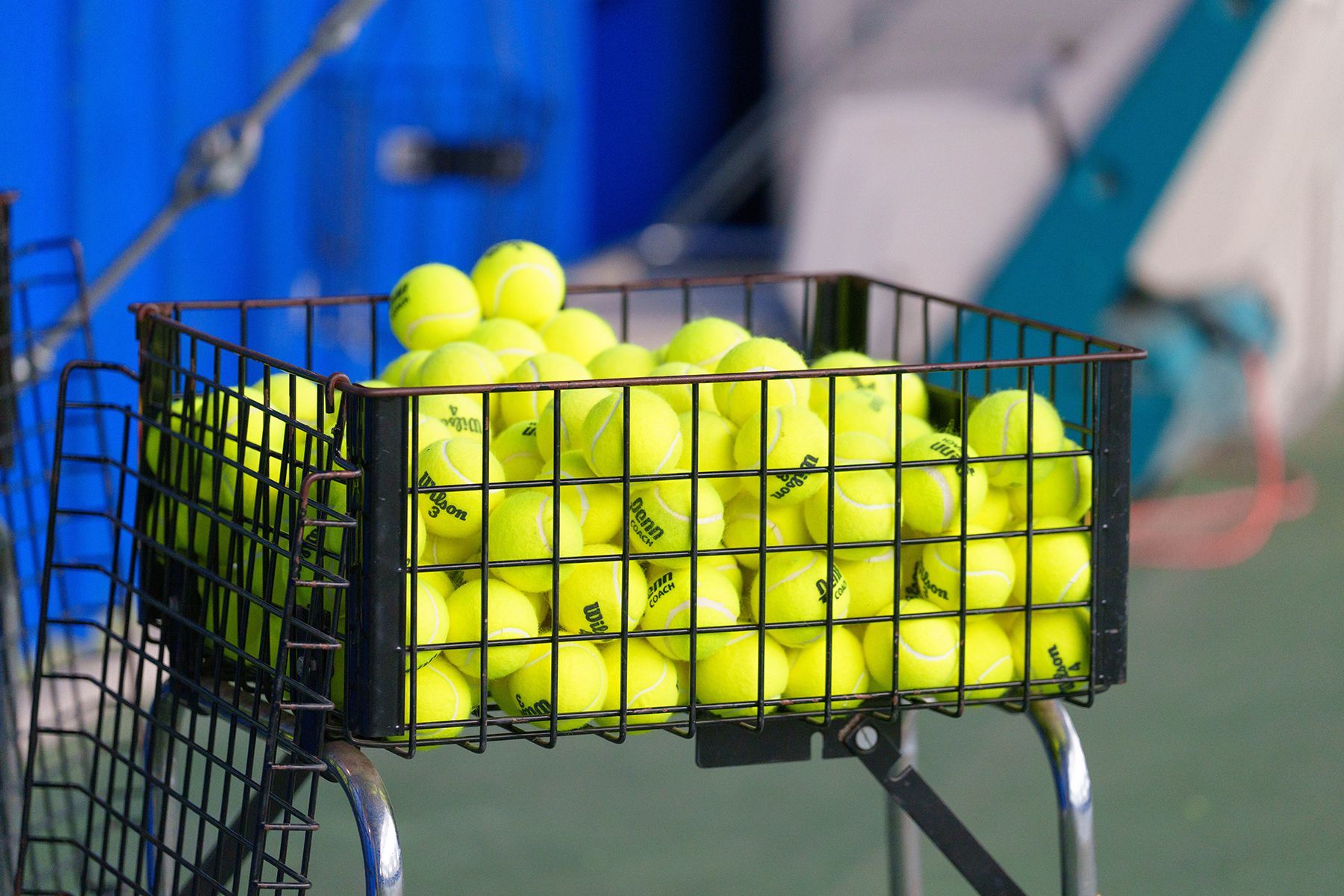 A basket filled with tennis balls on a tennis court