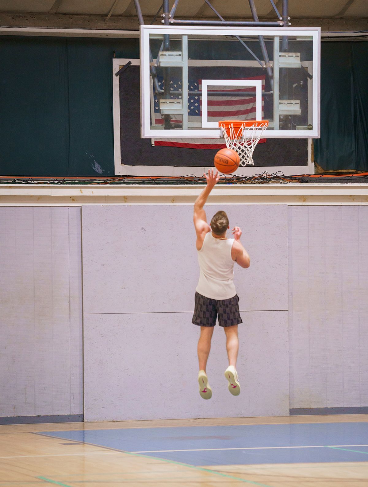 A person is jumping in the air to throw a basketball into a hoop.