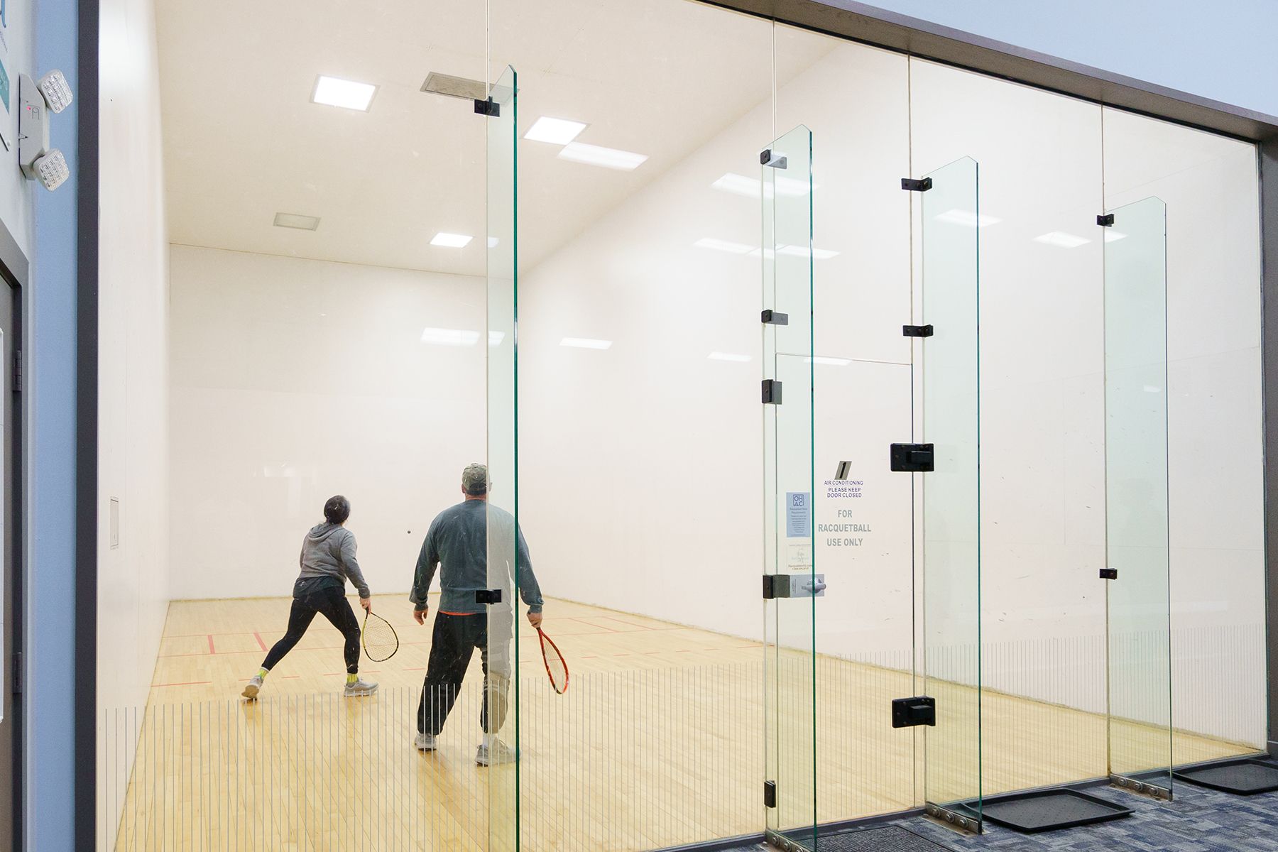 A man and a woman are playing squash on a court.