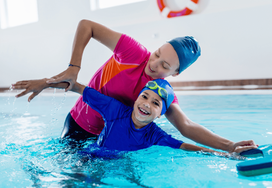 A woman is teaching a young boy how to swim in a swimming pool.