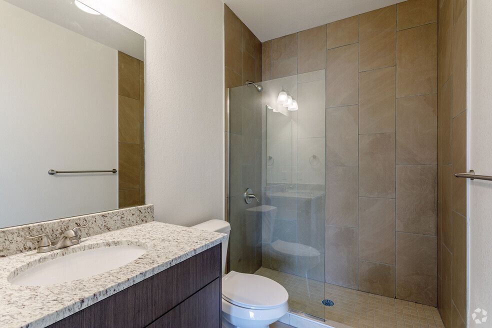 a bathroom with a toilet , sink , mirror and walk in shower .