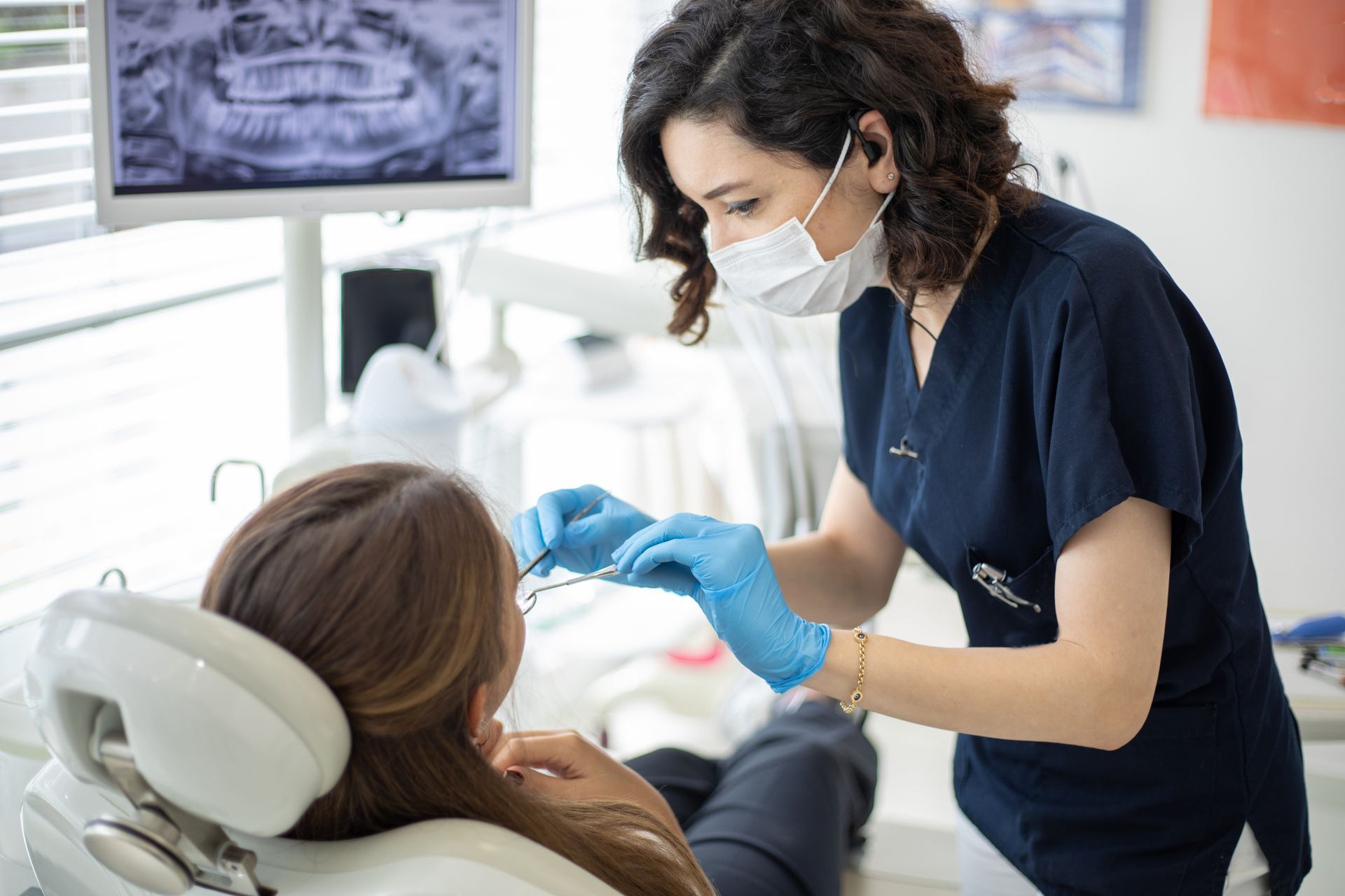 A dentist at JayHawk Dental in Lawrence, KS, is examining a patient's mouth during a routine check-u