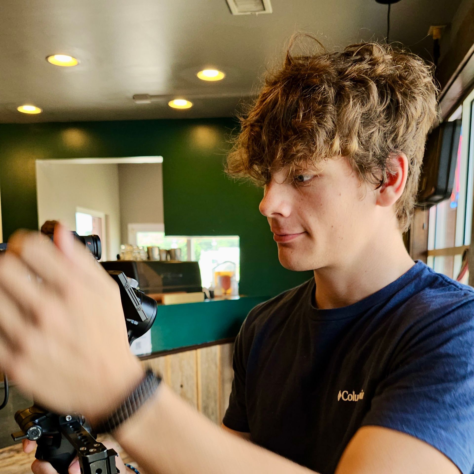 A young man in a blue columbia shirt is holding a camera