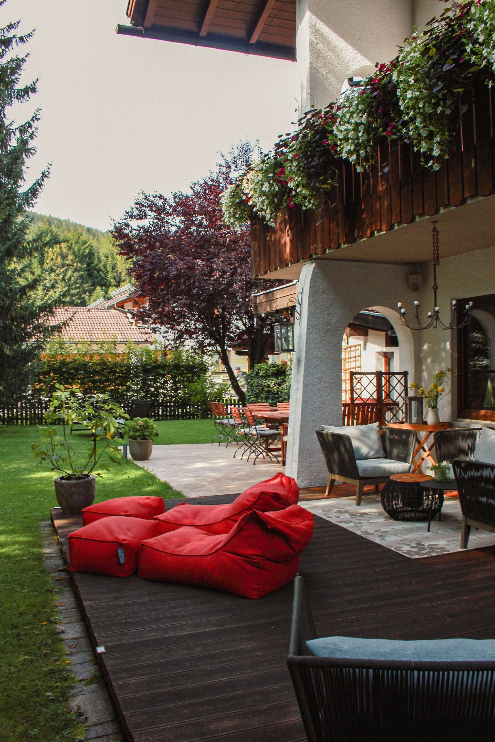 A patio with red bean bags and chairs in front of a house.