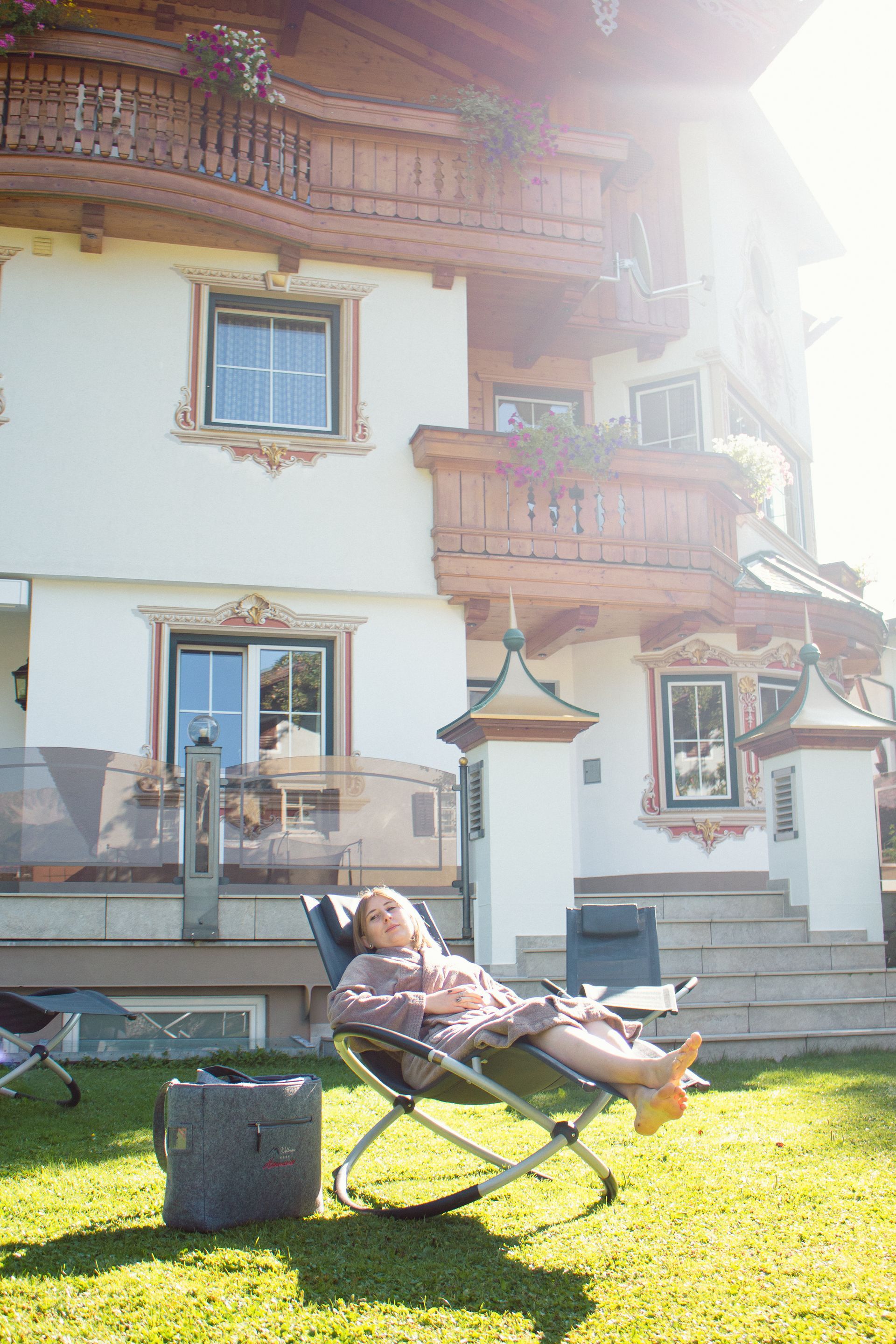 A woman is laying in a chair in front of a house.