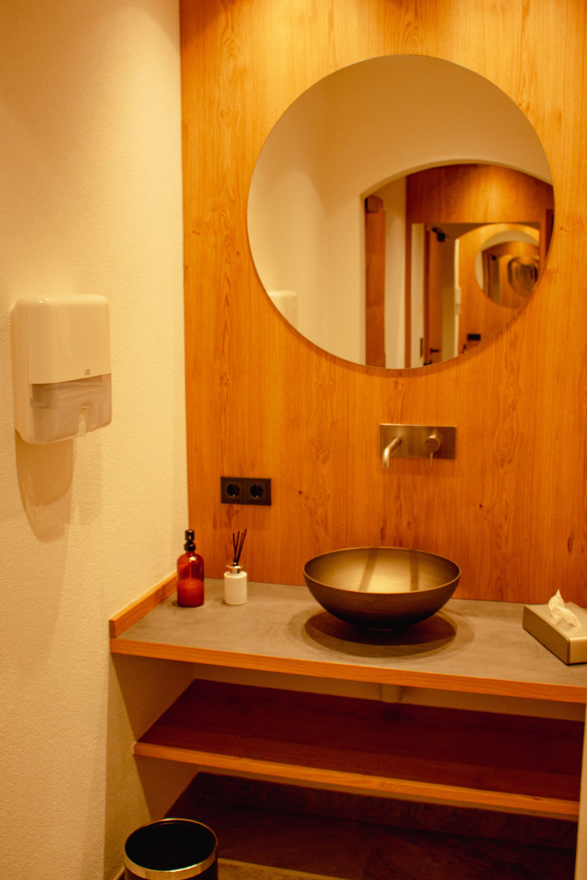 A bathroom with a sink and a round mirror