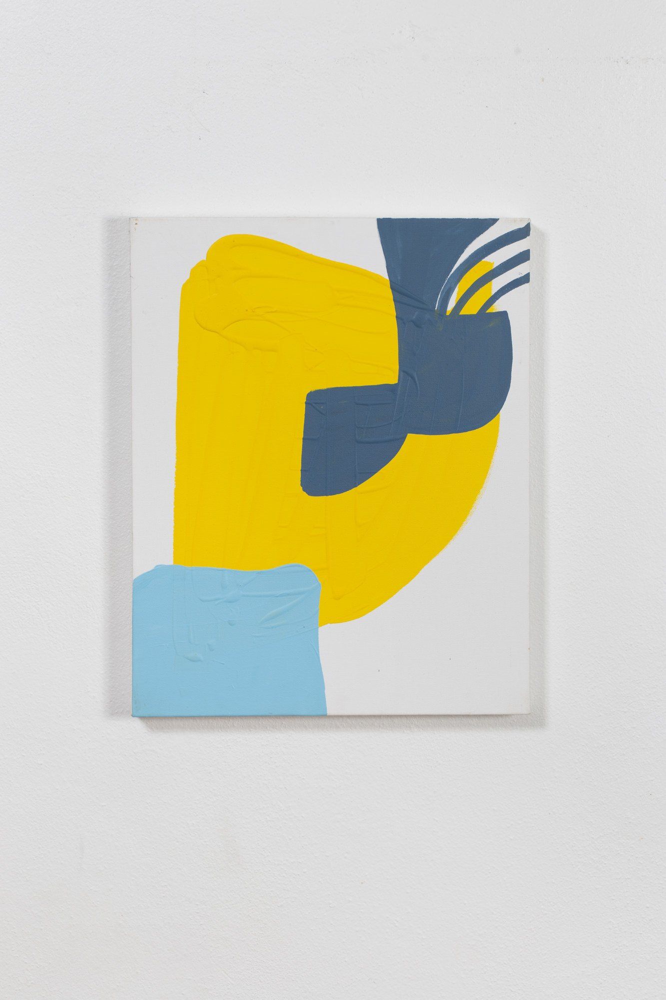 A yellow and blue painting is hanging on a white wall.