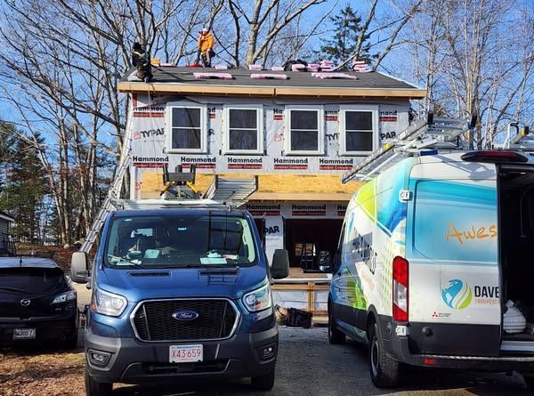 Two vans are parked in front of a house under construction.