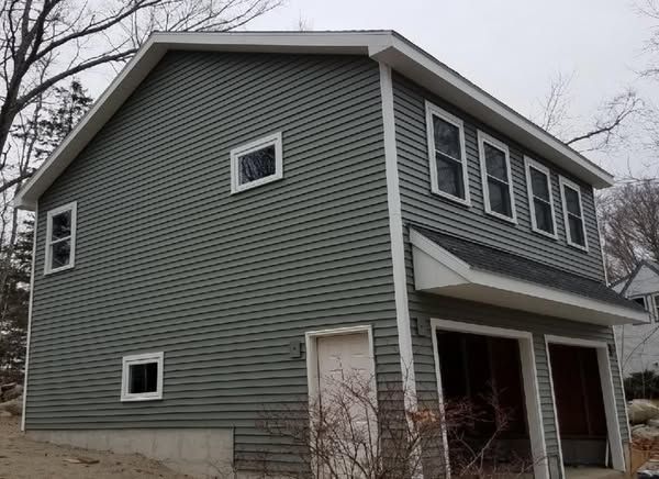 A green house with two garage doors and a roof