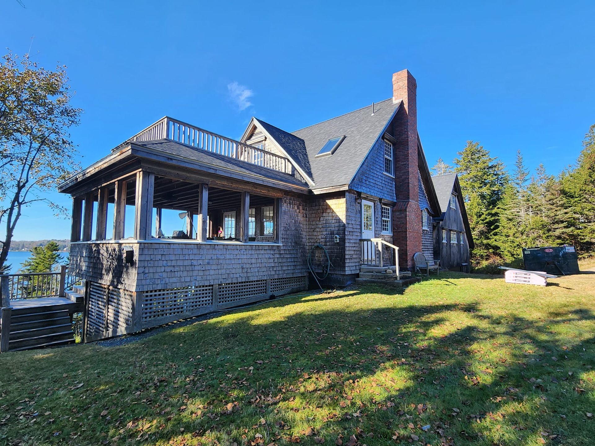 A large house is sitting on top of a lush green hill next to a body of water.