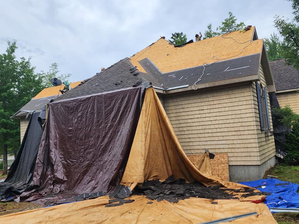 A house with a tarp covering the roof is being repaired.