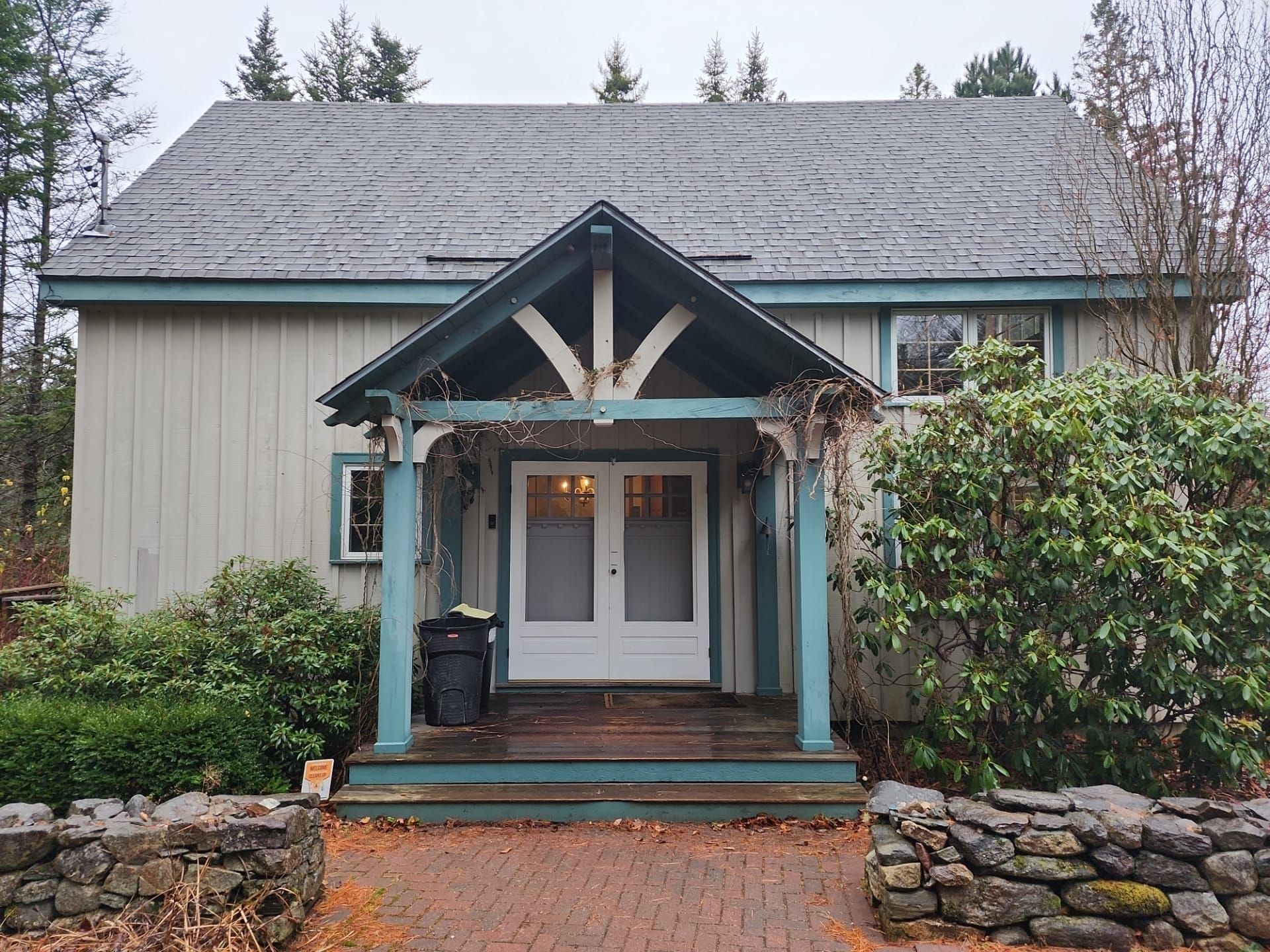 A small house with a porch and a stone wall