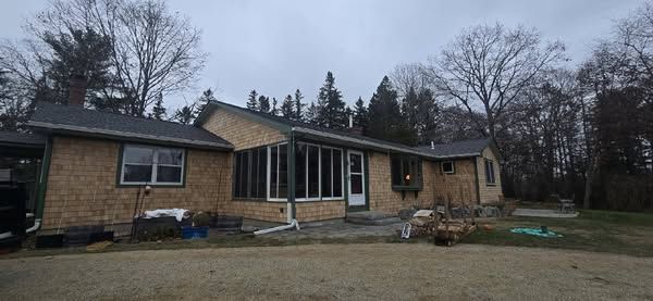 A large brick house with a gray roof is surrounded by trees.