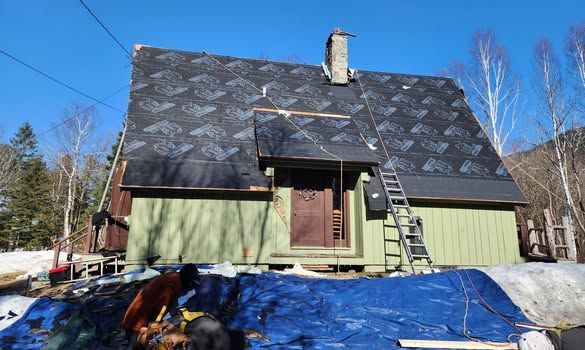 A green house with a black roof is being remodeled.