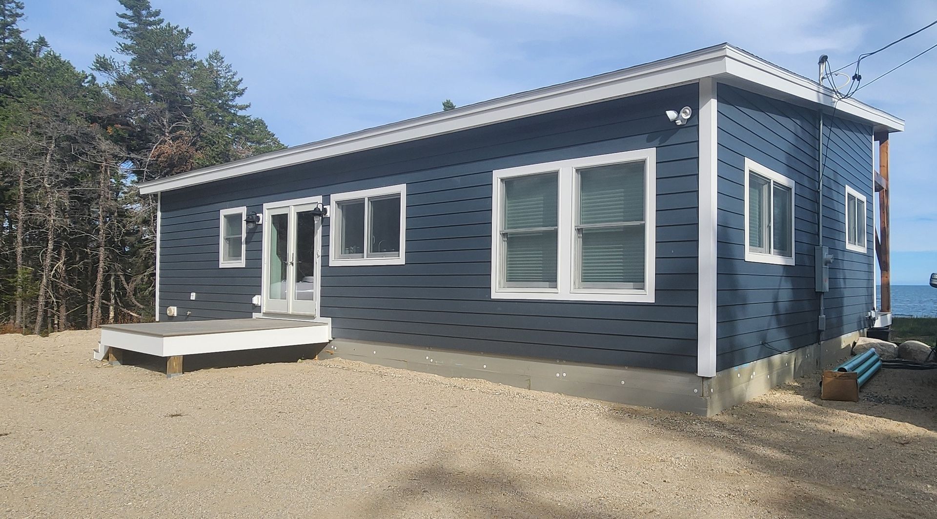 A small blue house with white windows and a deck