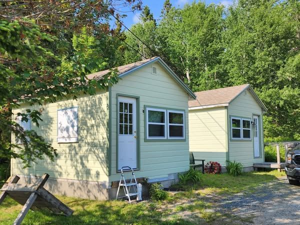 Two small houses are sitting next to each other on a dirt road.