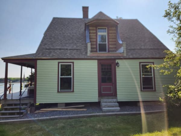 A green house with a porch and stairs