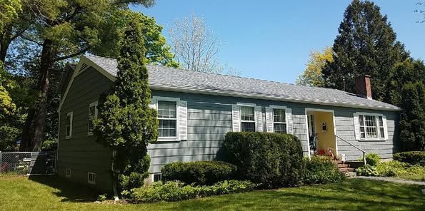 A small house with a gray roof and white shutters