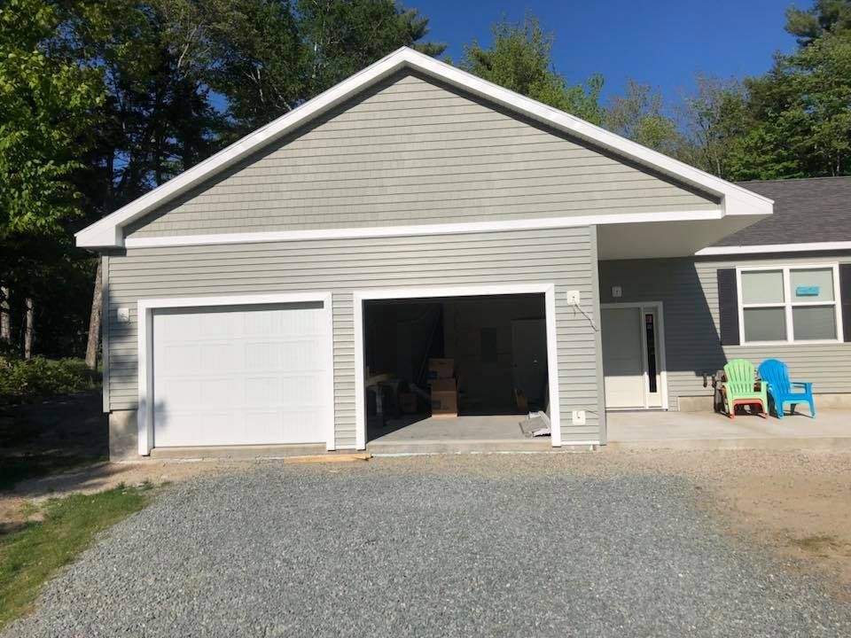 A house with a garage and two chairs in front of it.