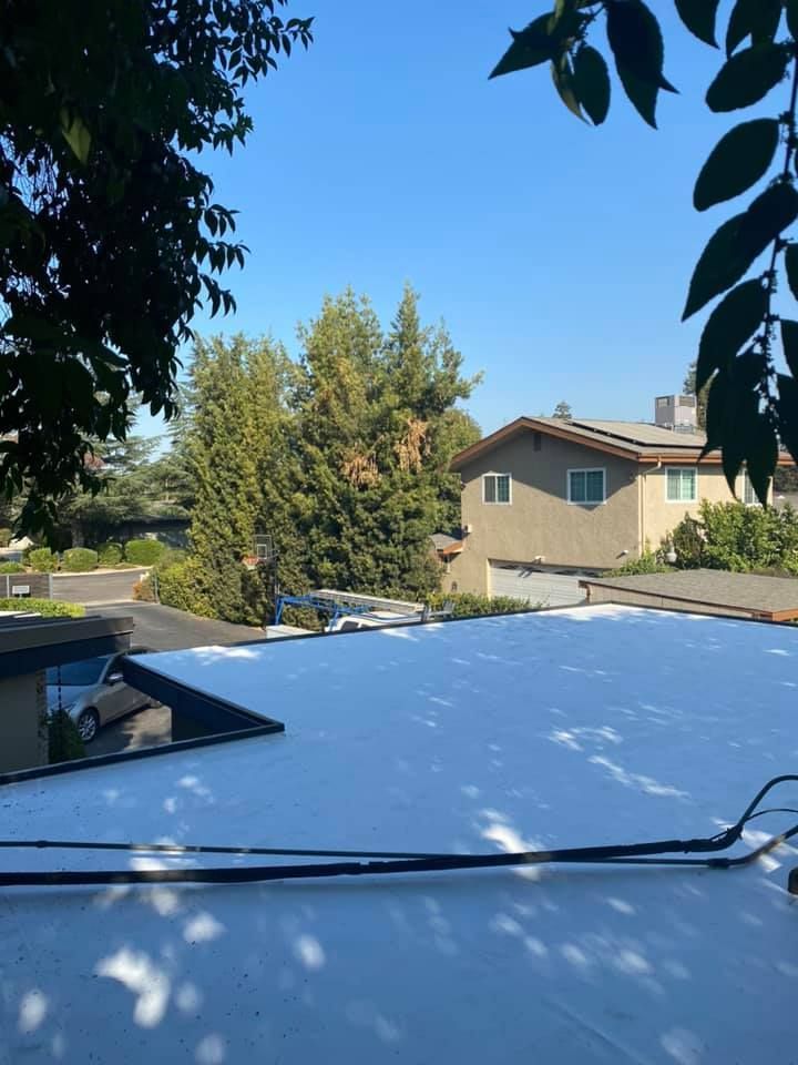 A white car is parked in front of a brick house.