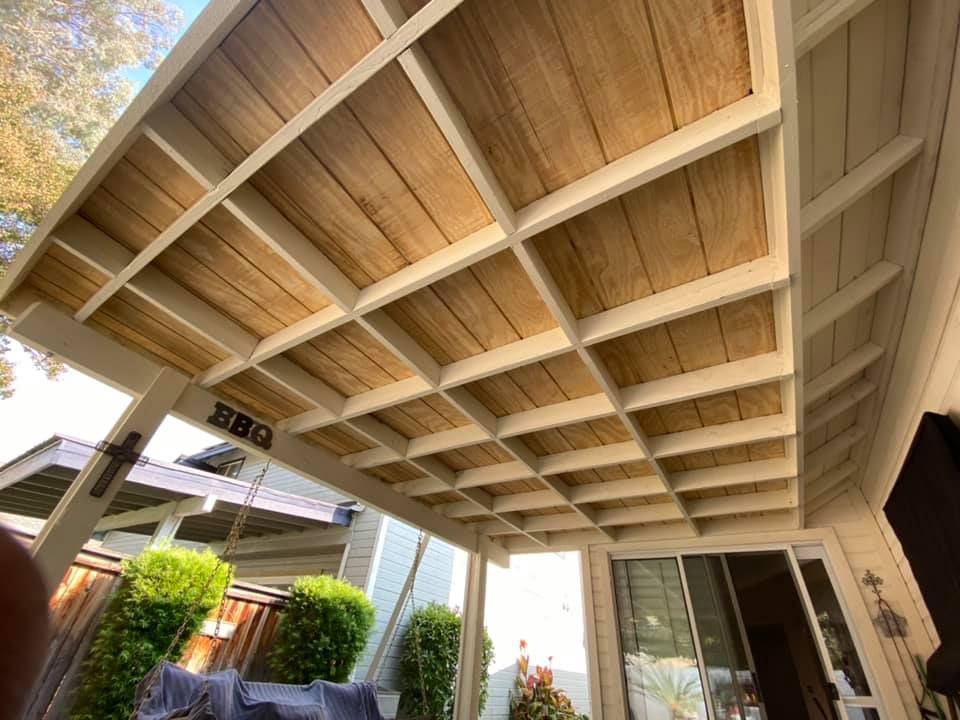 A patio with a wooden roof and a couch underneath it.