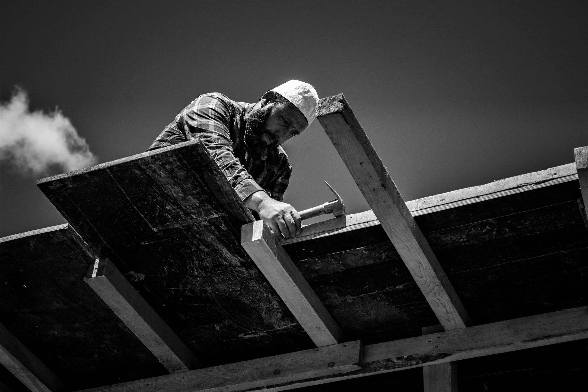 A black and white photo of a man working on a roof.