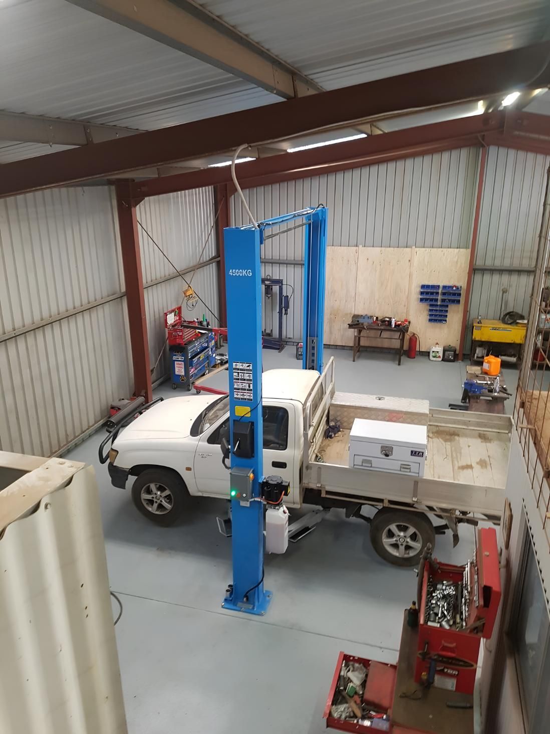 A White Truck Is Parked On A Lift In A Garage — Brake & Clutch Automotive Services In Ciccone, NT