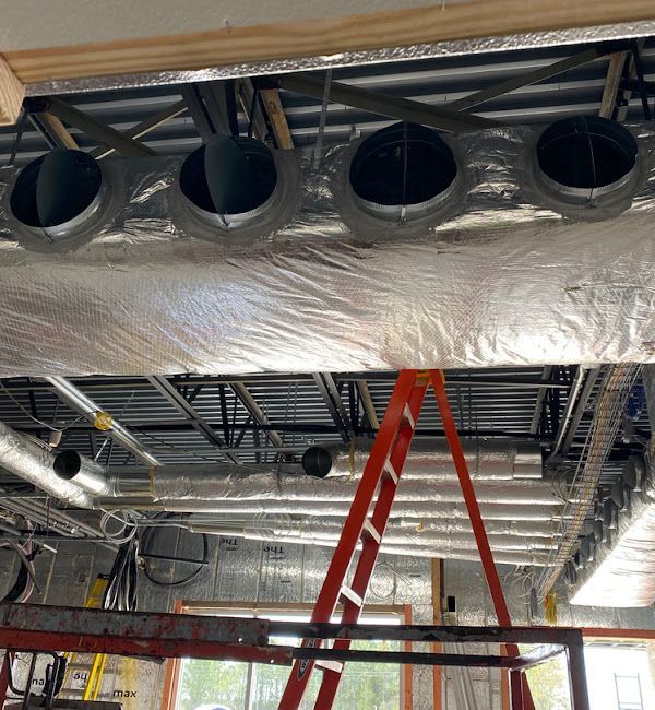 HVAC ductwork and insulation on ceiling, with an orange ladder and a metal frame below.