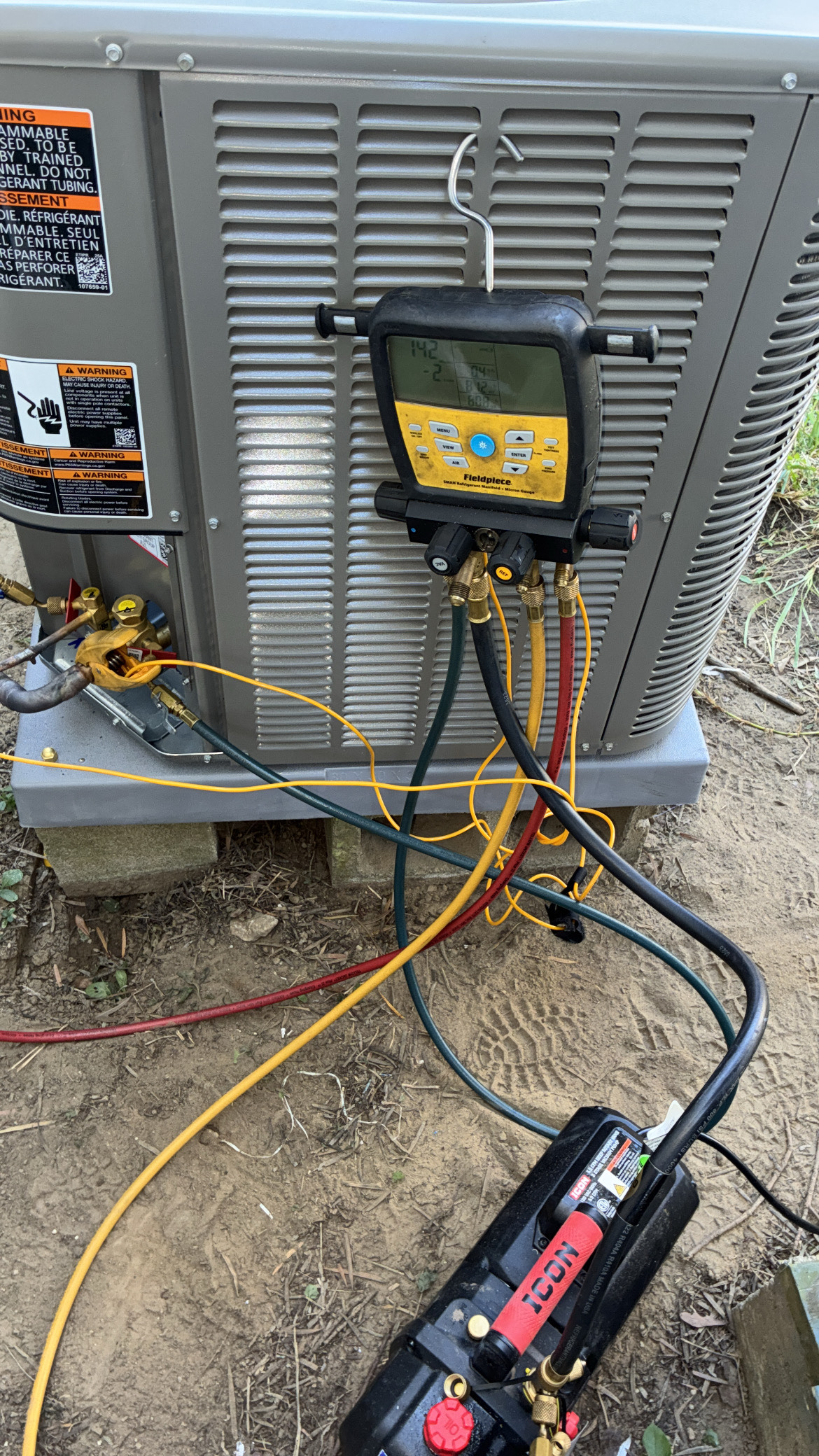 An HVAC technician servicing an air conditioning unit outside a brick building.