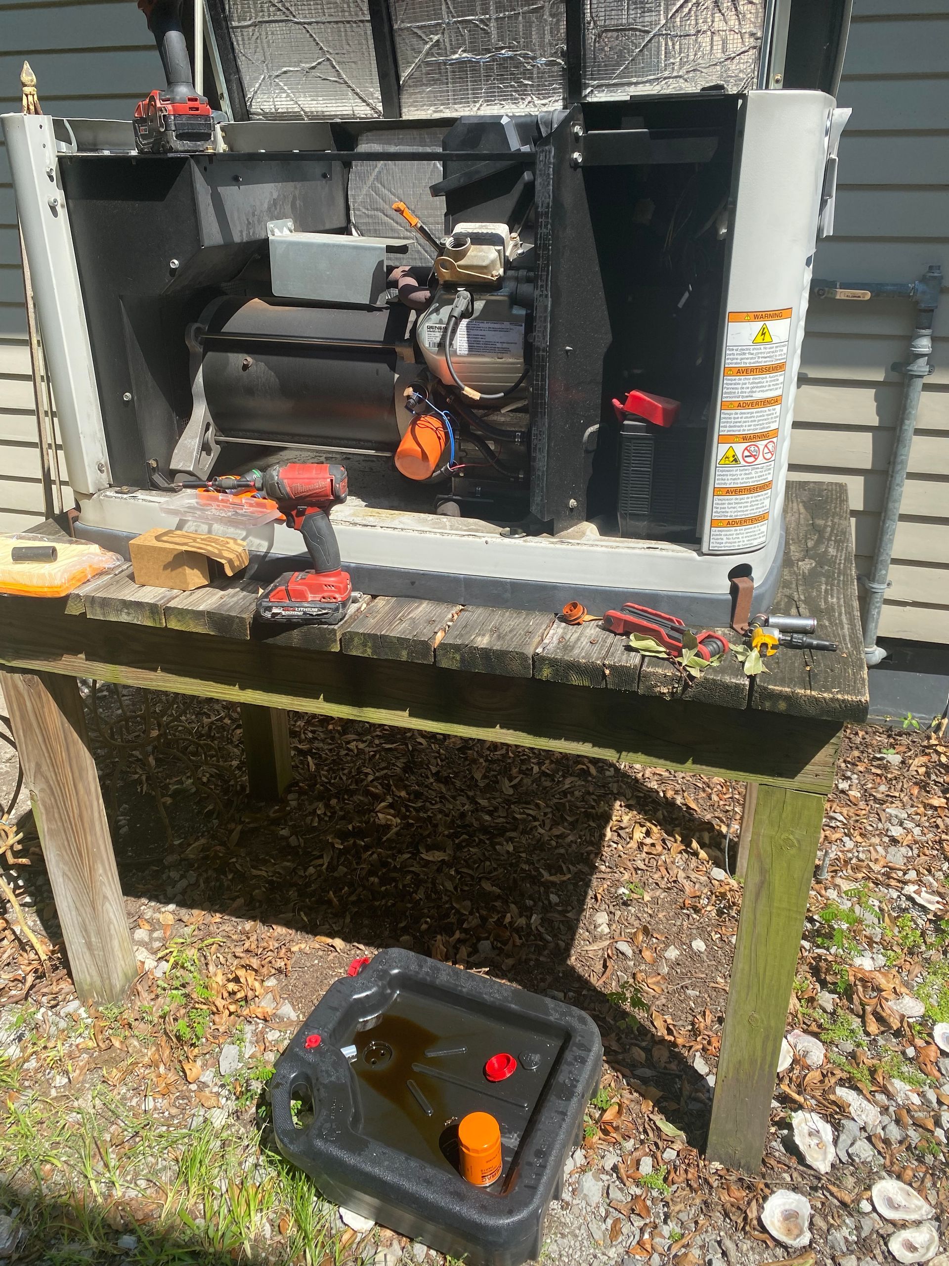 Person on a lift working on a light fixture attached to a tall pole, against a blue sky.