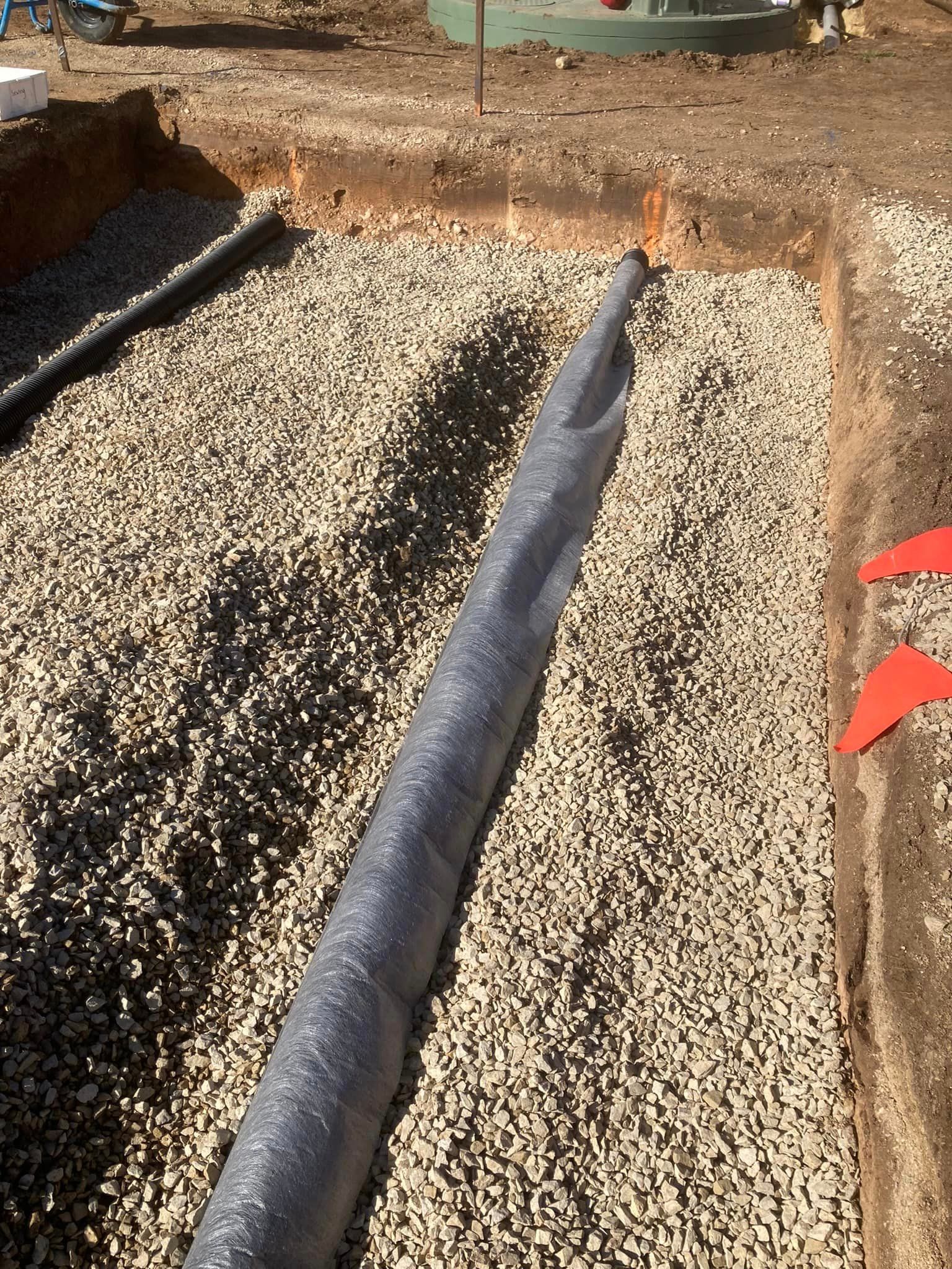 a large pipe is sitting on top of a pile of gravel .