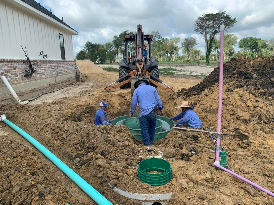 a group of men are working on a septic system in the dirt .