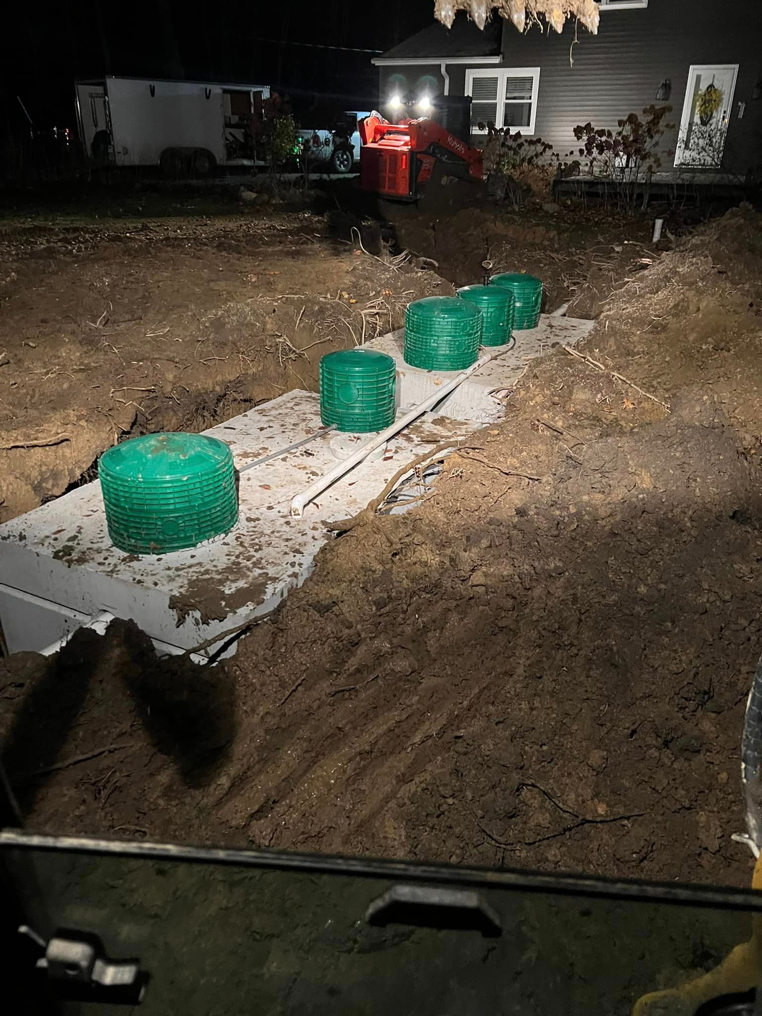 a septic system is being installed in a yard at night .